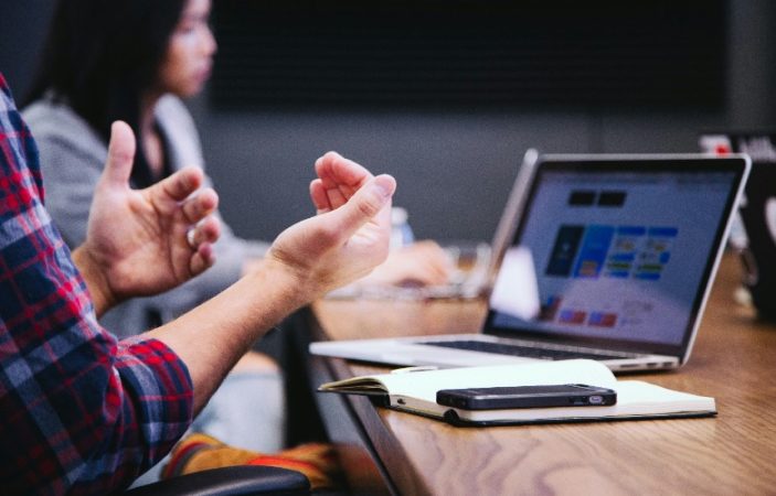 personne sur son ordinateur faisant des gestes de la main